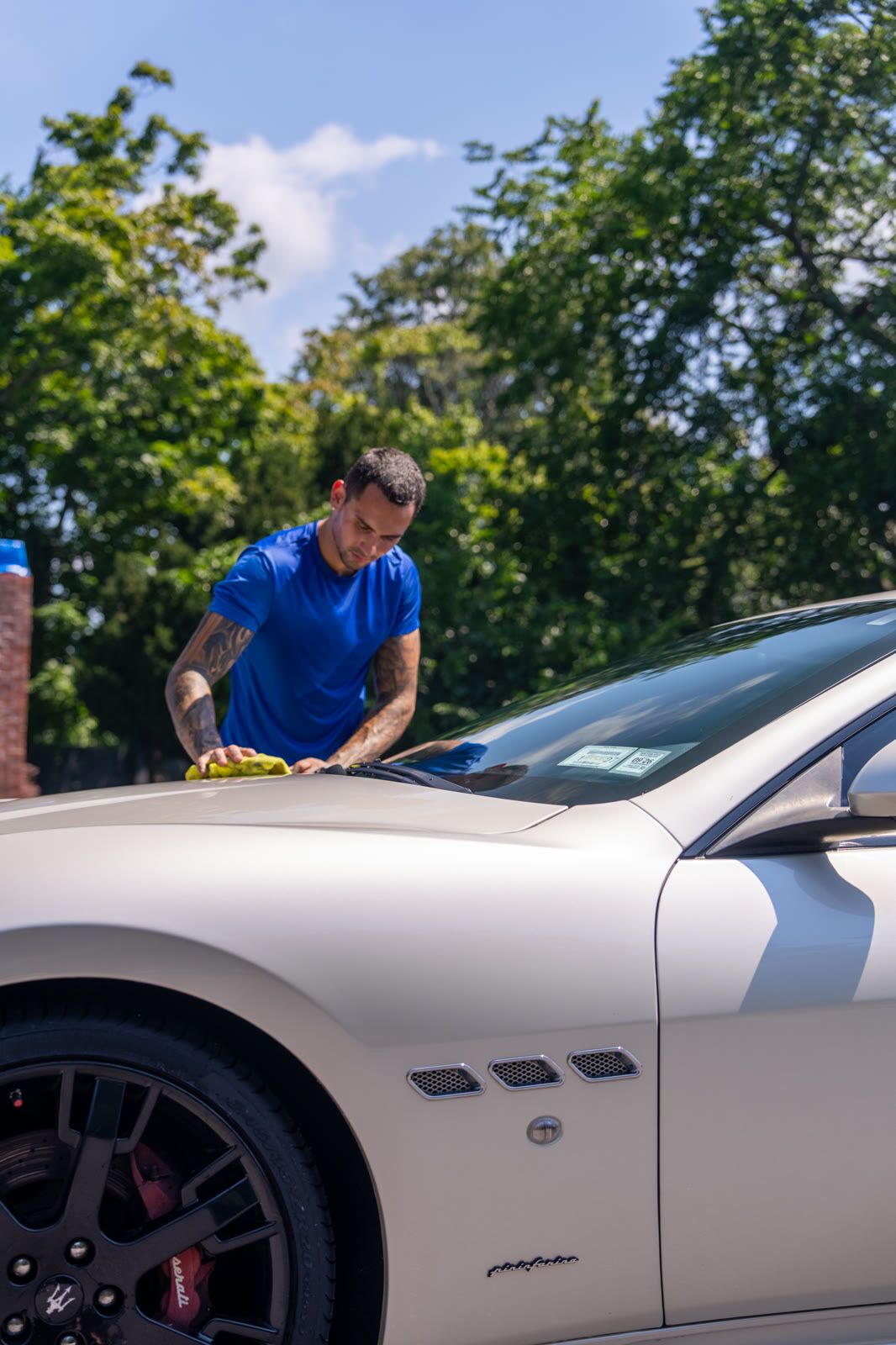 Front three-quarter of a pearl Maserati GranTurismo with red brake calipers during detail