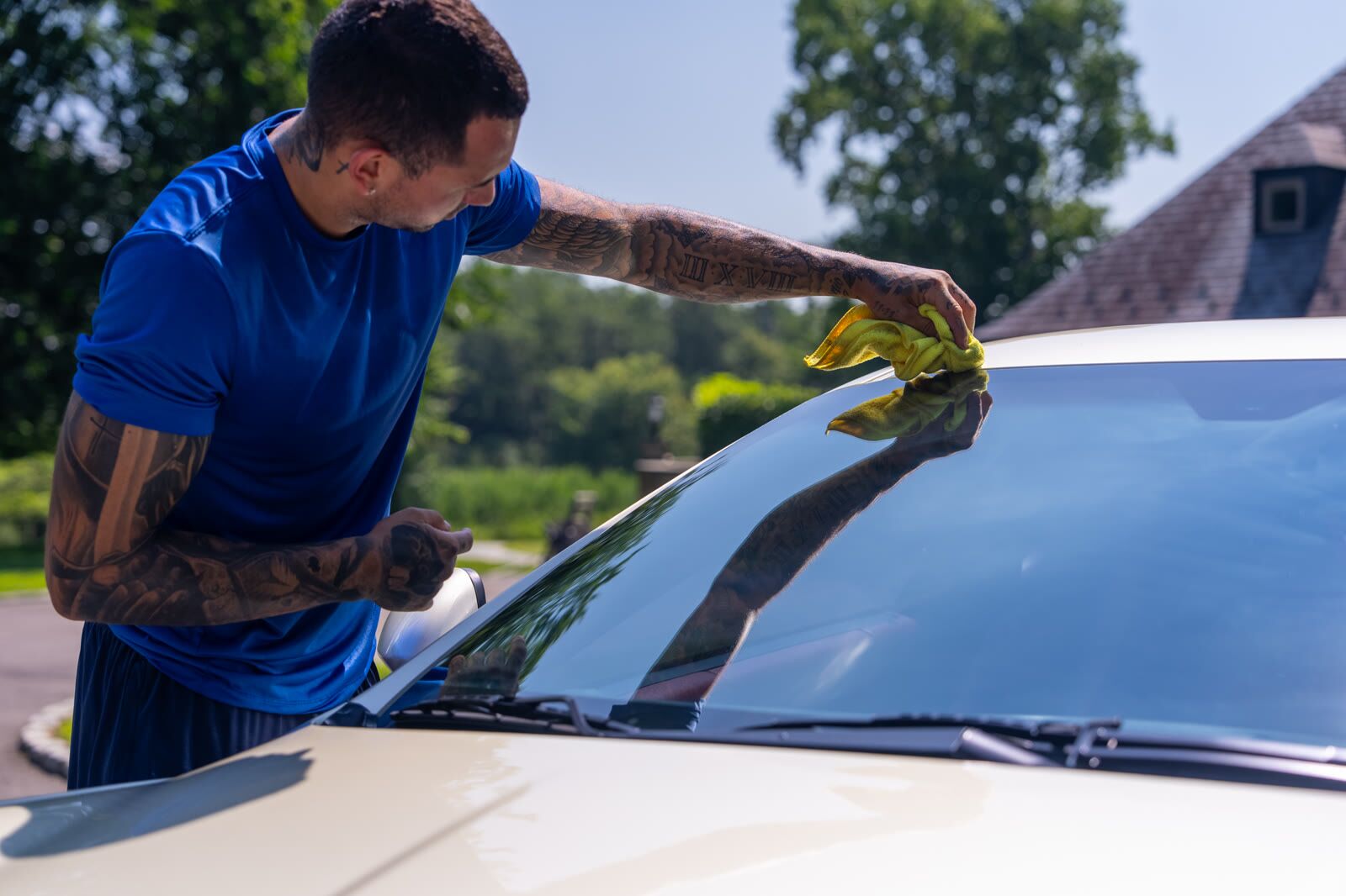Detailer wiping the windshield of a pearl Maserati GranTurismo during exterior detail