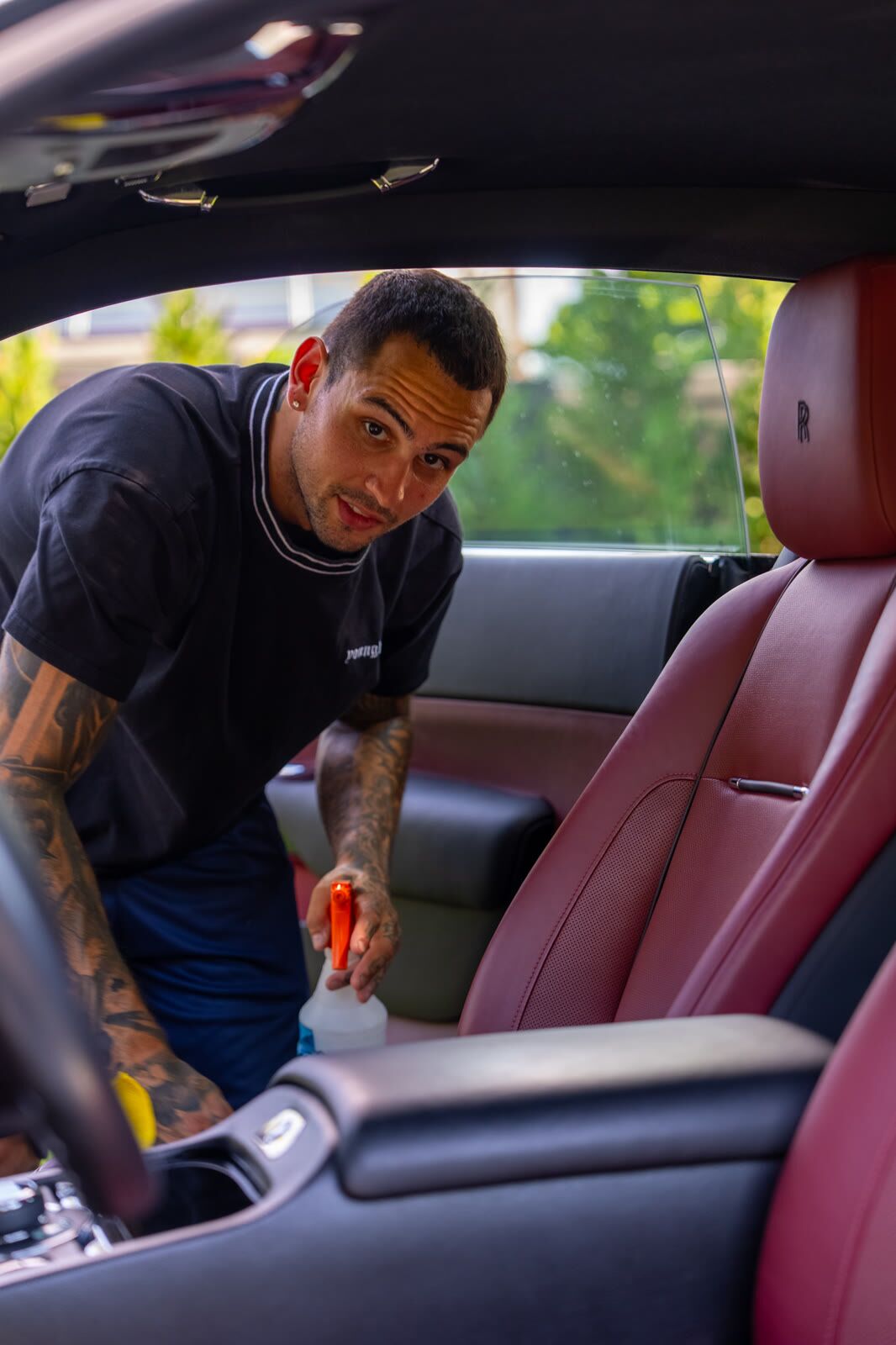 Detailer looking to camera while cleaning a Rolls-Royce Wraith seat