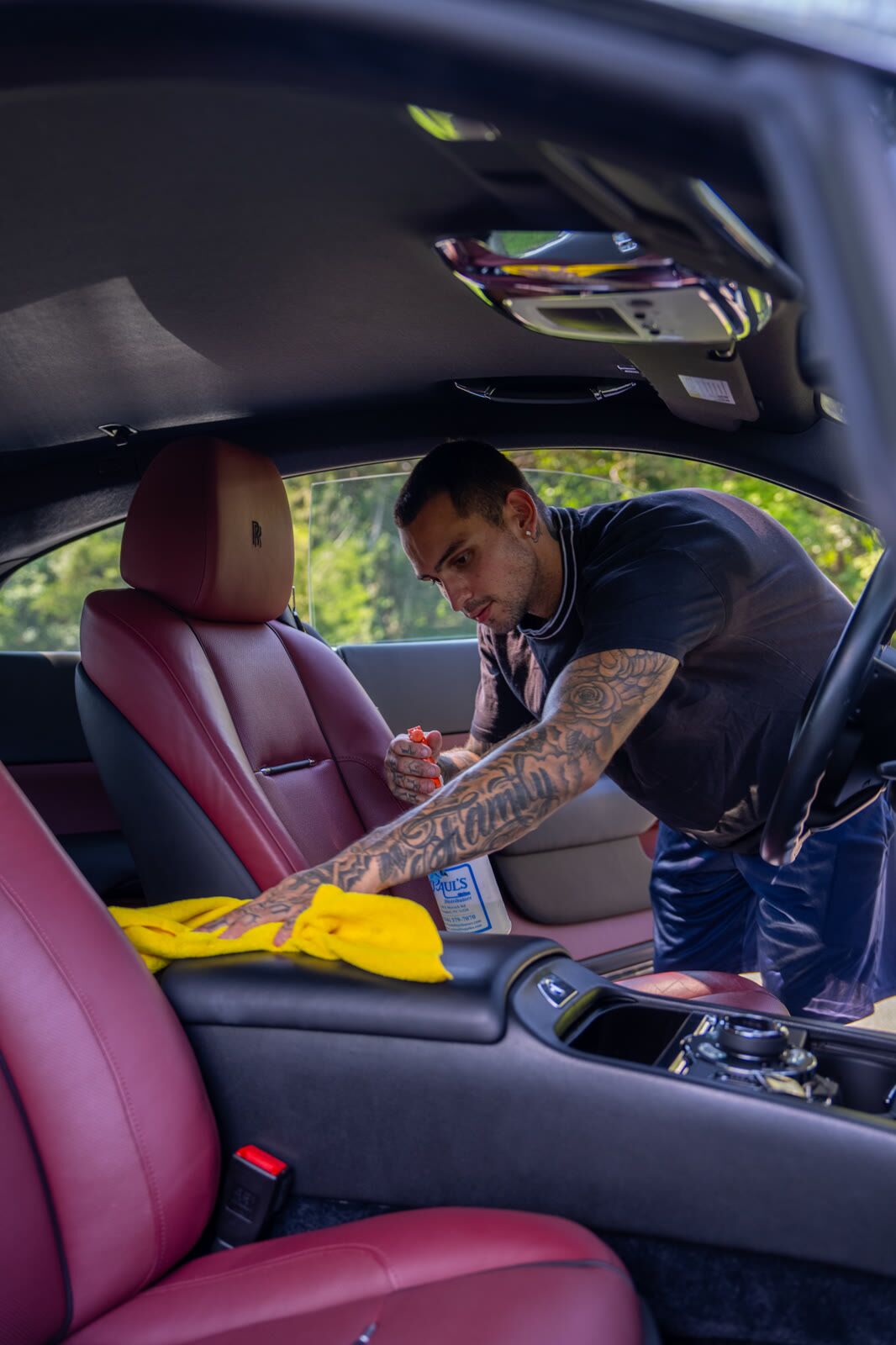 Burgundy Rolls-Royce Wraith seat being wiped down during a leather conditioning pass